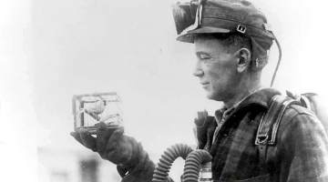 R. Thornburg shows a small cage with a canary used for testing carbon monoxide gas in 1928.