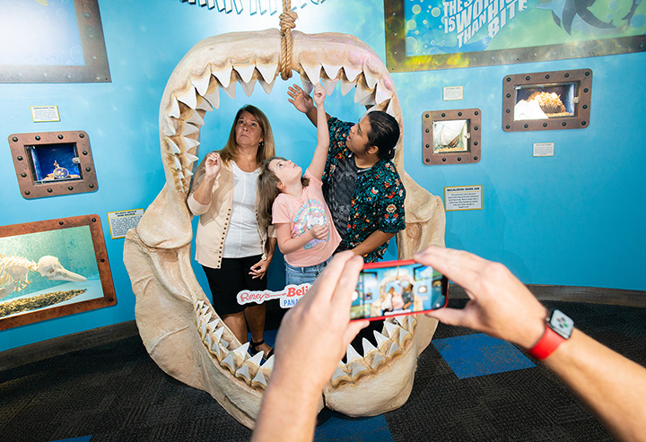 A family stands in awe within the jaws of a megalodon shark for a photo op at Ripley's Believe It or Not! Panama City Beach.