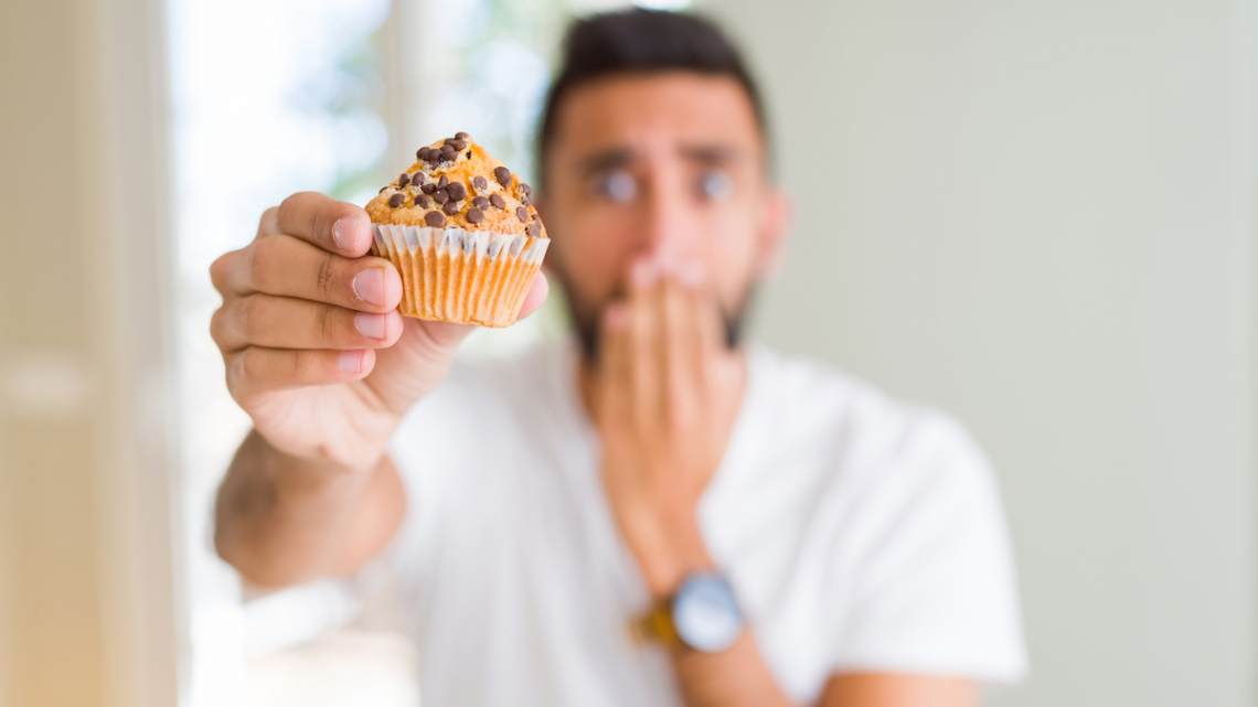 man eating chocolate chips muffin