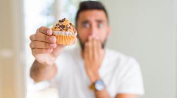 man eating chocolate chips muffin